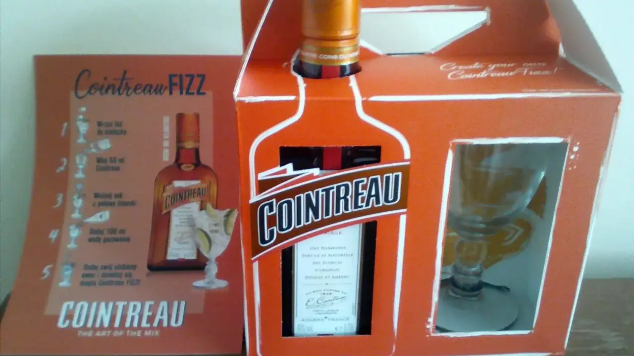 Zestaw Cointreau z kieliszkiem i instrukcją przygotowania drinka Cointreau Fizz. Ten pomarańczowy likier, znany jako Cointreau triple sec, to klucz do orzeźwiających koktajli.