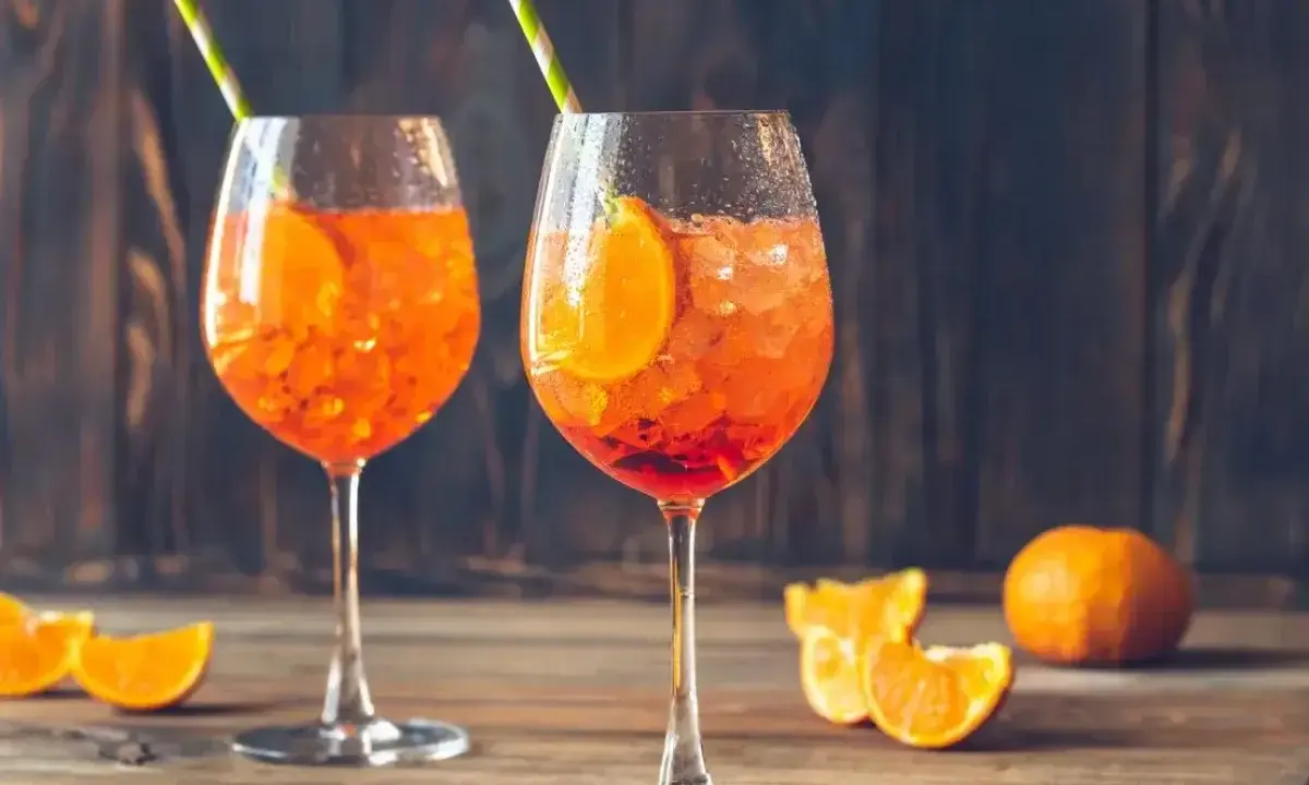 Dwa orzeźwiające Aperol Spritz z plasterkami pomarańczy i słomkami. Idealne aperol proporcje na letni wieczór.