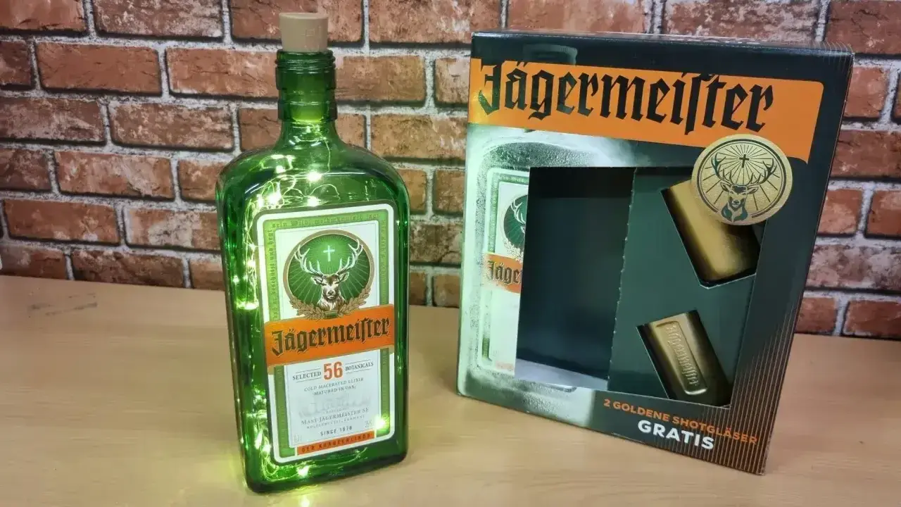 Butelka Jägermeistera z lampkami i zestawem kieliszków. Poznaj, jak smakuje jagermeister – ziołowy eliksir.