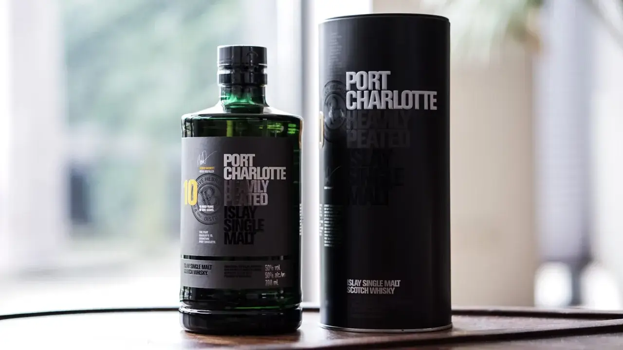 Port Charlotte Heavily Peated 10, whisky single malt z Islay, w zielonej butelce i czarnej tubie.