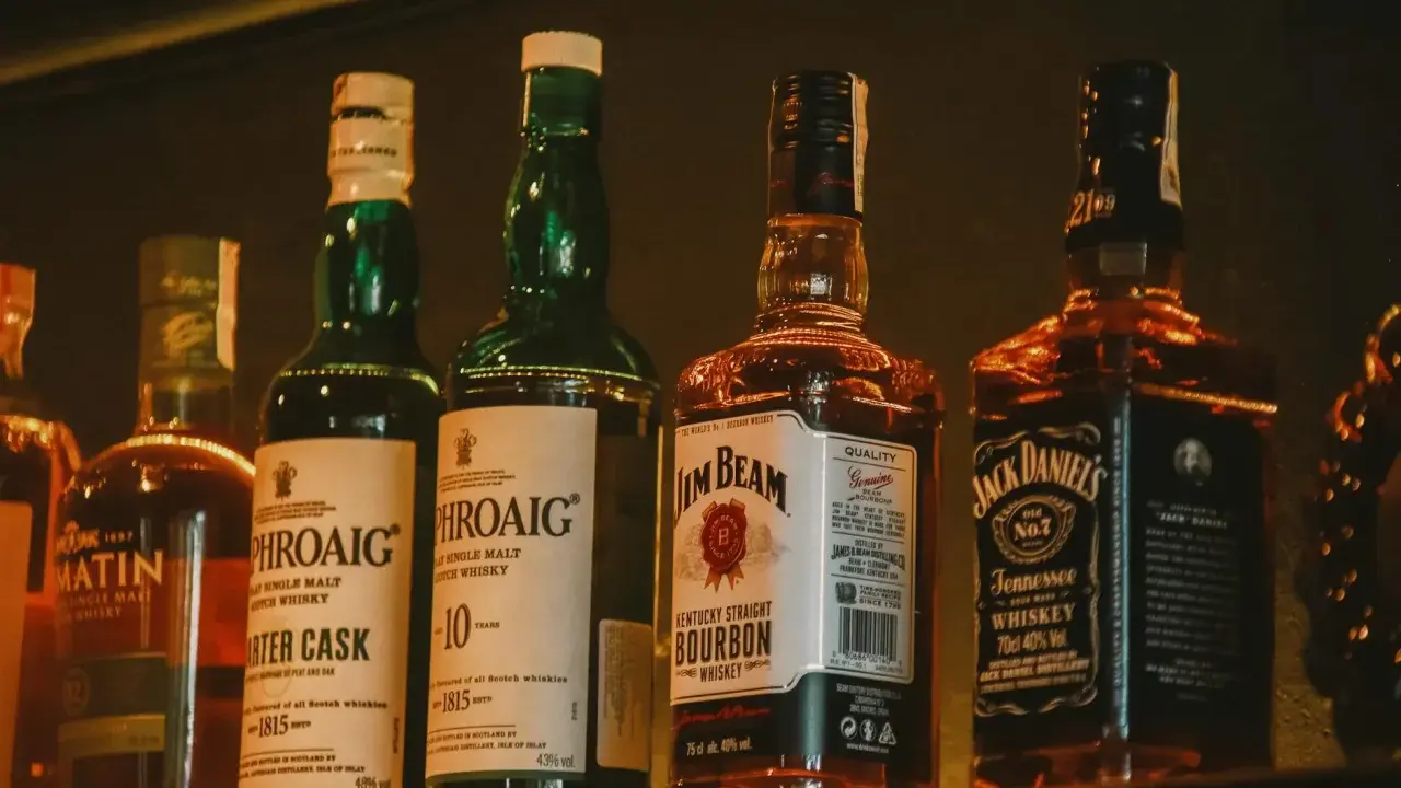 Rząd butelek whisky: Laphroaig, Jim Beam i Jack Daniel's.