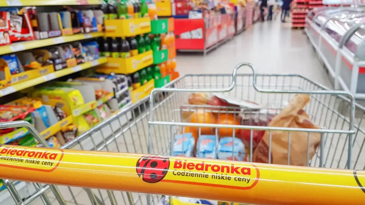 Wózek sklepowy z zakupami w Biedronce, widok z perspektywy klienta.