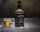 Burbon co to? Butelka Jack Daniel's Tennessee Whiskey i szklanka z drinkiem, lodem i rozbryzgami.