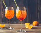 Dwa orzeźwiające Aperol Spritz z plasterkami pomarańczy i słomkami. Idealne aperol proporcje na letni wieczór.