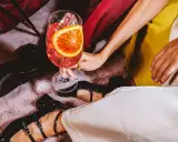 Elegancka kobieta z drinkiem, w którym widać plaster pomarańczy i lód. Zastanawiasz się, wermut co to? To aromatyzowane wino, idealne na letnie wieczory.