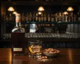 Butelka amaretto, szklanka z lodem i skórką pomarańczy, miseczka migdałów. Idealny zestaw, by dowiedzieć się, amaretto co to.