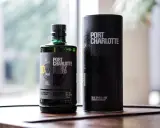 Port Charlotte Heavily Peated 10, whisky single malt z Islay, w zielonej butelce i czarnej tubie.