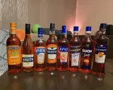 Rząd butelek z pomarańczowym, lekkim alkoholem, idealnym na letnie wieczory. Wśród nich Monte Santi, Aperitivo, Apice, Ranginino, Buon Spritz i Aparancio.