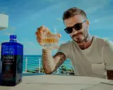 David Beckham z kieliszkiem Haig Club whisky, na tle błękitnego nieba i morza. Idealny moment na relaks.