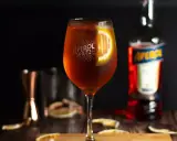 Orzeźwiający Aperol Spritz z plastrem pomarańczy, obok butelki Aperolu. Poznaj różne rodzaje Aperolu i jego zastosowania.