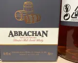 Elegancka butelka Abrachan Blended Malt Scotch Whisky, potrójnie dojrzewająca w dębie, z beczkami na etykiecie.