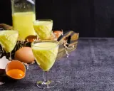 Żółty likier jajeczny w kieliszkach, obok jajka i skorupki. Czy adwokat to alkohol? Tak, to pyszny, słodki likier.