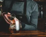 Barman nalewa whisky Glenlivet 12 do szklanki z lodem. Wiele pozytywnych opinii potwierdza jej jakość.