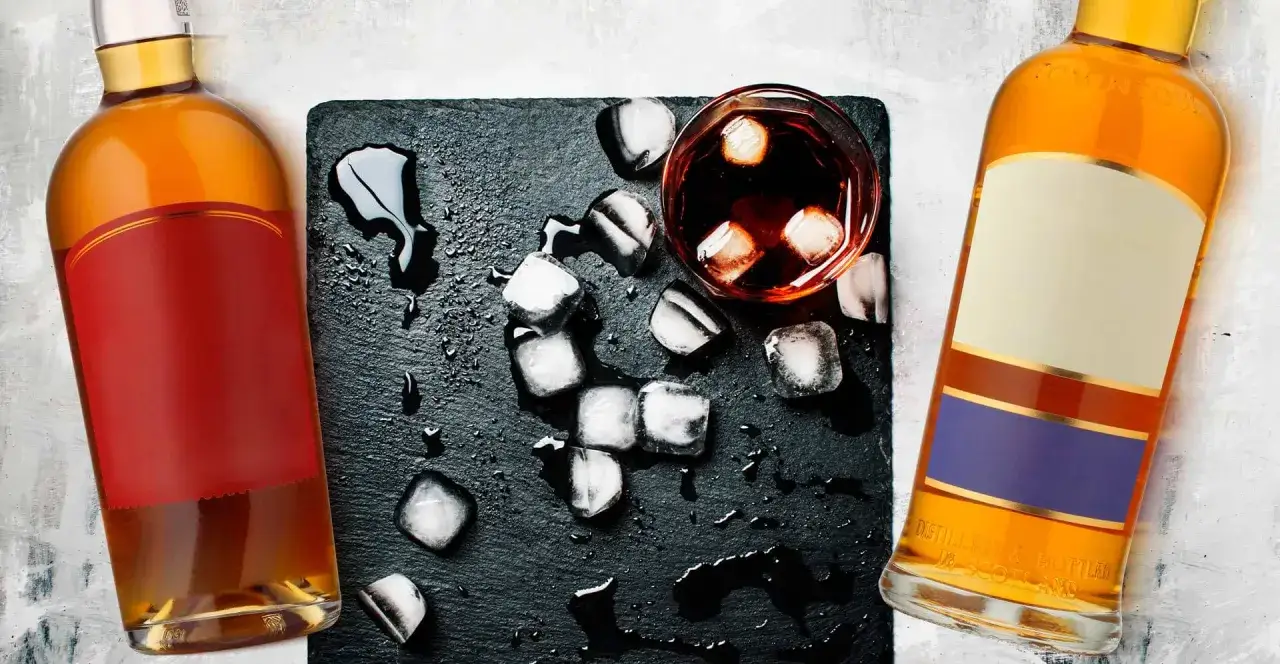 Dwie butelki bursztynowego trunku, kostki lodu i szklanka z napojem. Tak się pisze whisky, gdy chcesz poczuć smak Szkocji.