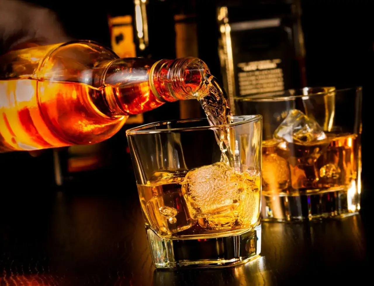 Lejący się złocisty płyn z butelki do szklanki z lodem. To idealny moment na degustację Ballantines 12 years.