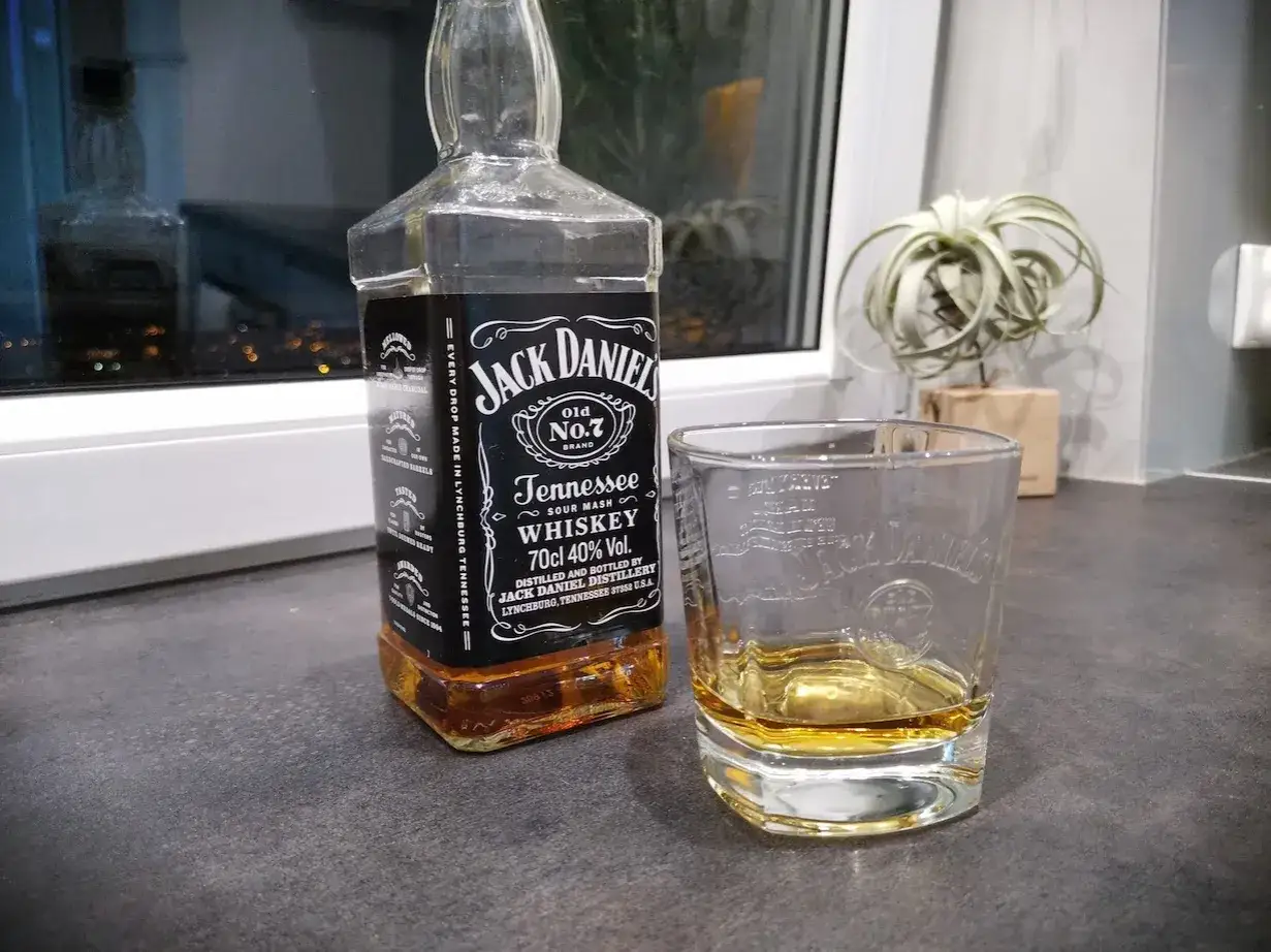 Butelka Jack Daniel's i szklanka z whisky. Z czym pić Jack Daniel's? Najlepiej z lodem lub colą.