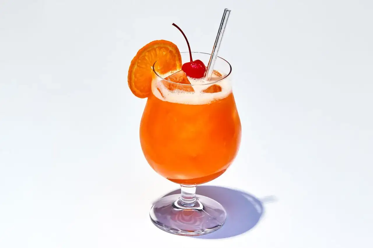 Orzeźwiający drink z pomarańczą i wiśnią, z nutą Cointreau triple sec, na białym tle.