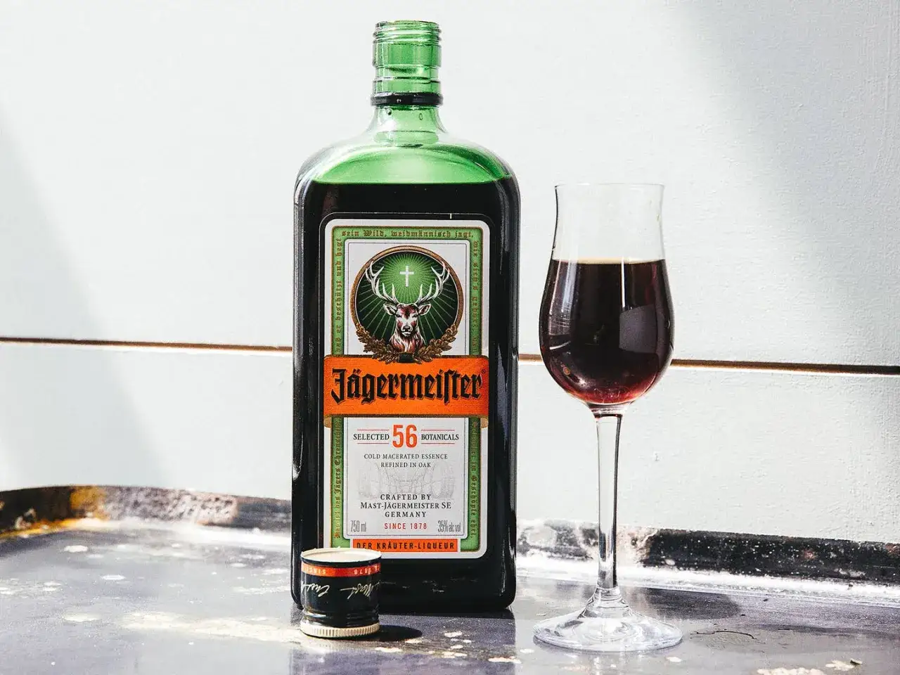 Butelka Jägermeister i kieliszek z ciemnym likierem. Idealny na wieczorne spotkania.