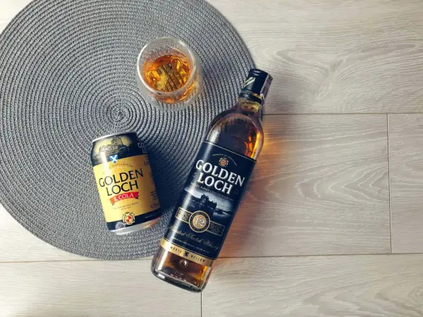 Złoty **Golden Loch** whisky i napój z colą, gotowe do degustacji.