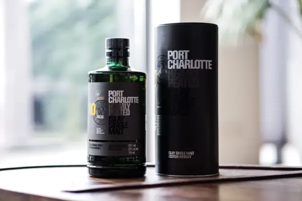 Port Charlotte Heavily Peated 10, whisky single malt z Islay, w zielonej butelce i czarnej tubie.