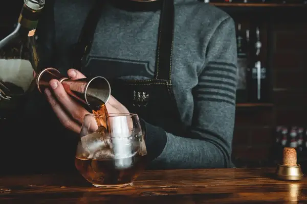 Barman nalewa whisky Glenlivet 12 do szklanki z lodem. Wiele pozytywnych opinii potwierdza jej jakość.