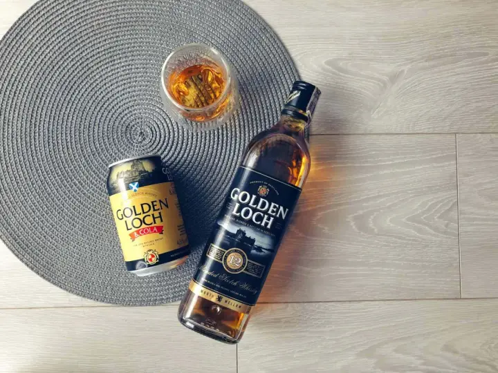 Złoty **Golden Loch** whisky i napój z colą, gotowe do degustacji.